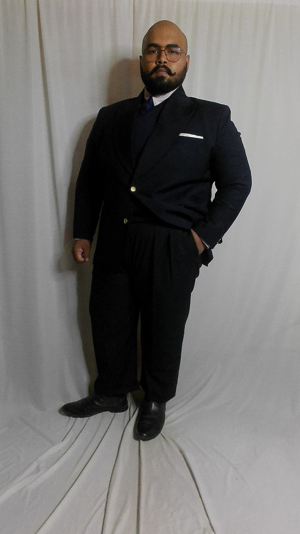 Man in a Super 140s Navy suit standing against a white background
