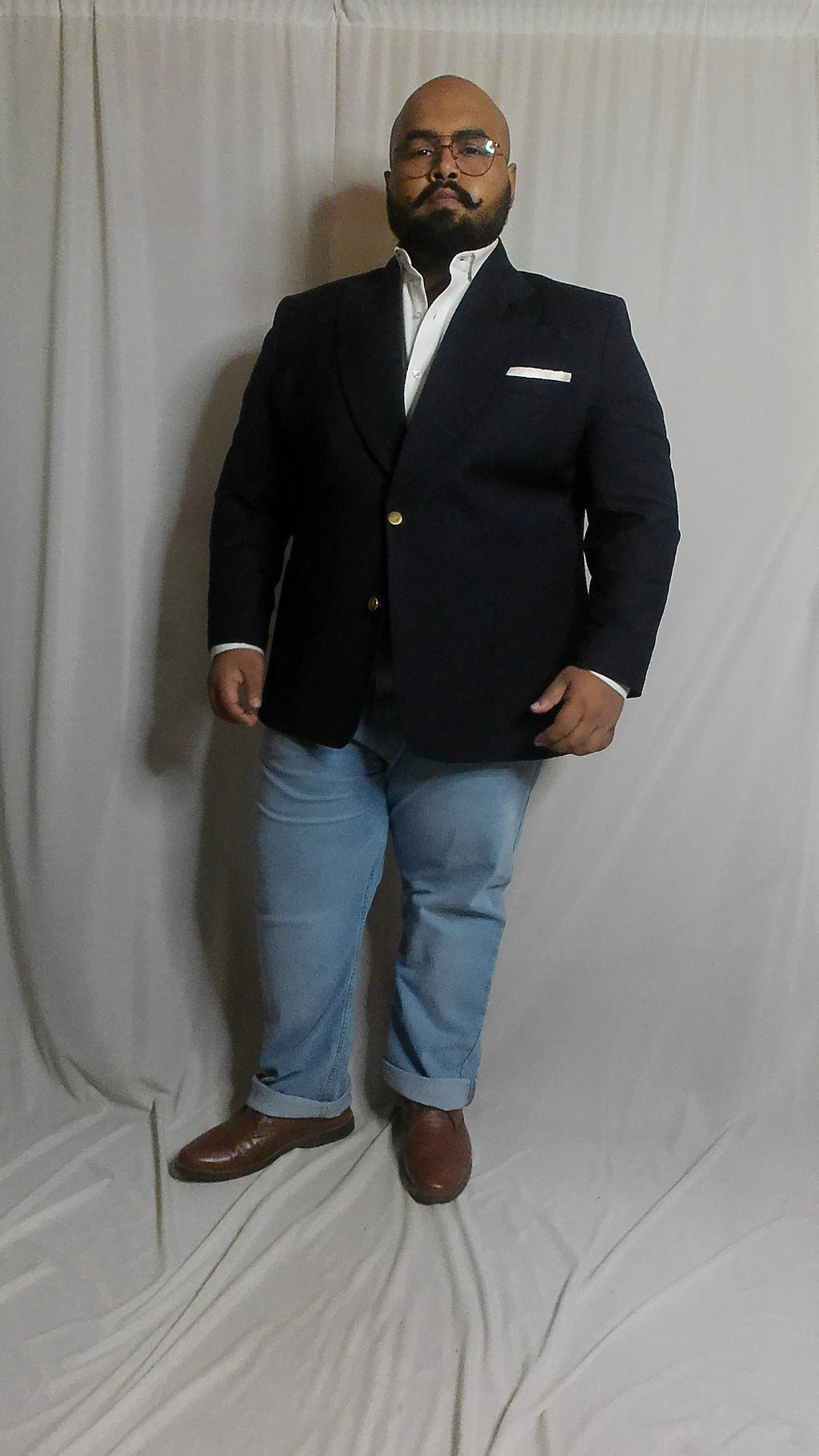 Plus sized Man wearing a navy blazer and light blue jeans on a white background