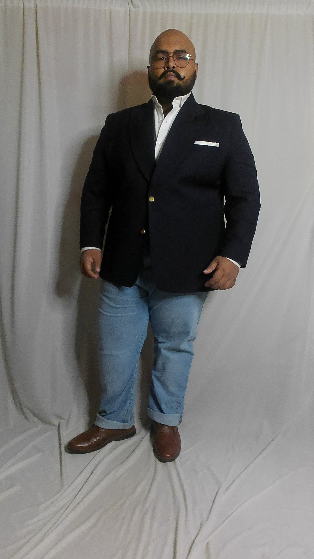 Plus sized Man wearing a navy blazer and light blue jeans on a white background