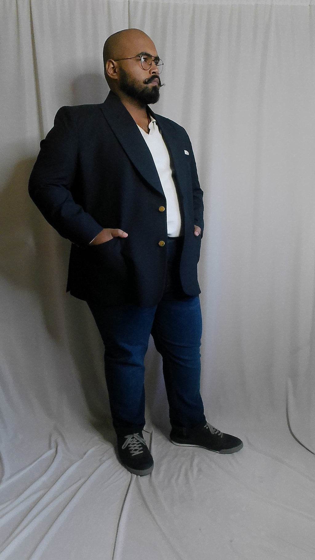 Man wearing a navy blazer and dark wash denim with white shirt on a white background
