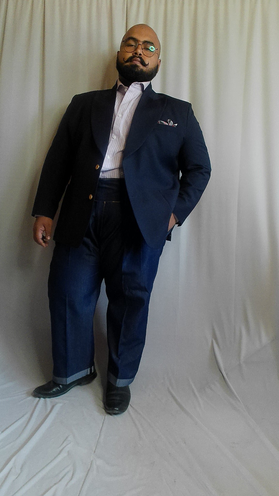 Man wearing a navy blazer with dark wash denim trouser against a white background