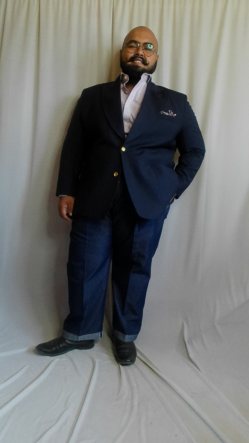 A man in a blue jeans and navy blazer on a white background