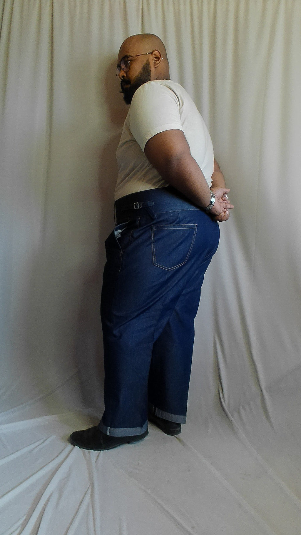 Person wearing a white shirt and blue  denimoveralls standing on a white background