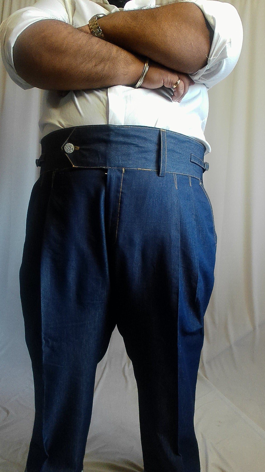 Person wearing a white shirt and blue gurkha denim trouser on a plain background