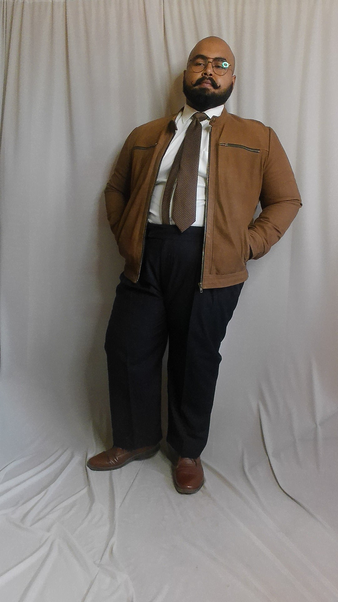 Man wearing a brown jacket and navy blue pants on a white background